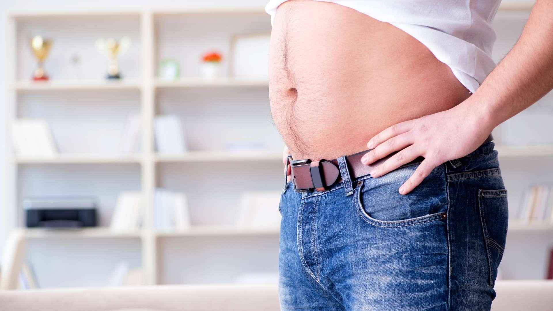 Homme de profil avec jean et tee-shirt blanc relevé et petit ventre