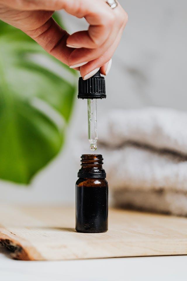 Main de femme qui tient un bouchon-pipette de flacon d'huiles essentielles