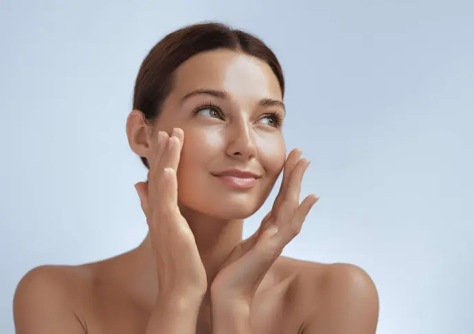 Femme avec une belle peau qui touche ses joues avec ses mains