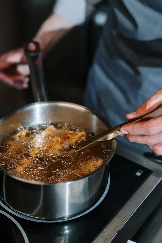 Homme avec tablier bleu avec casserole sur la gazinière devant lui